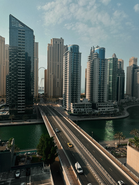 Aerial view of modern skyscrapers and canal in Dubai Marina during a sunny day.