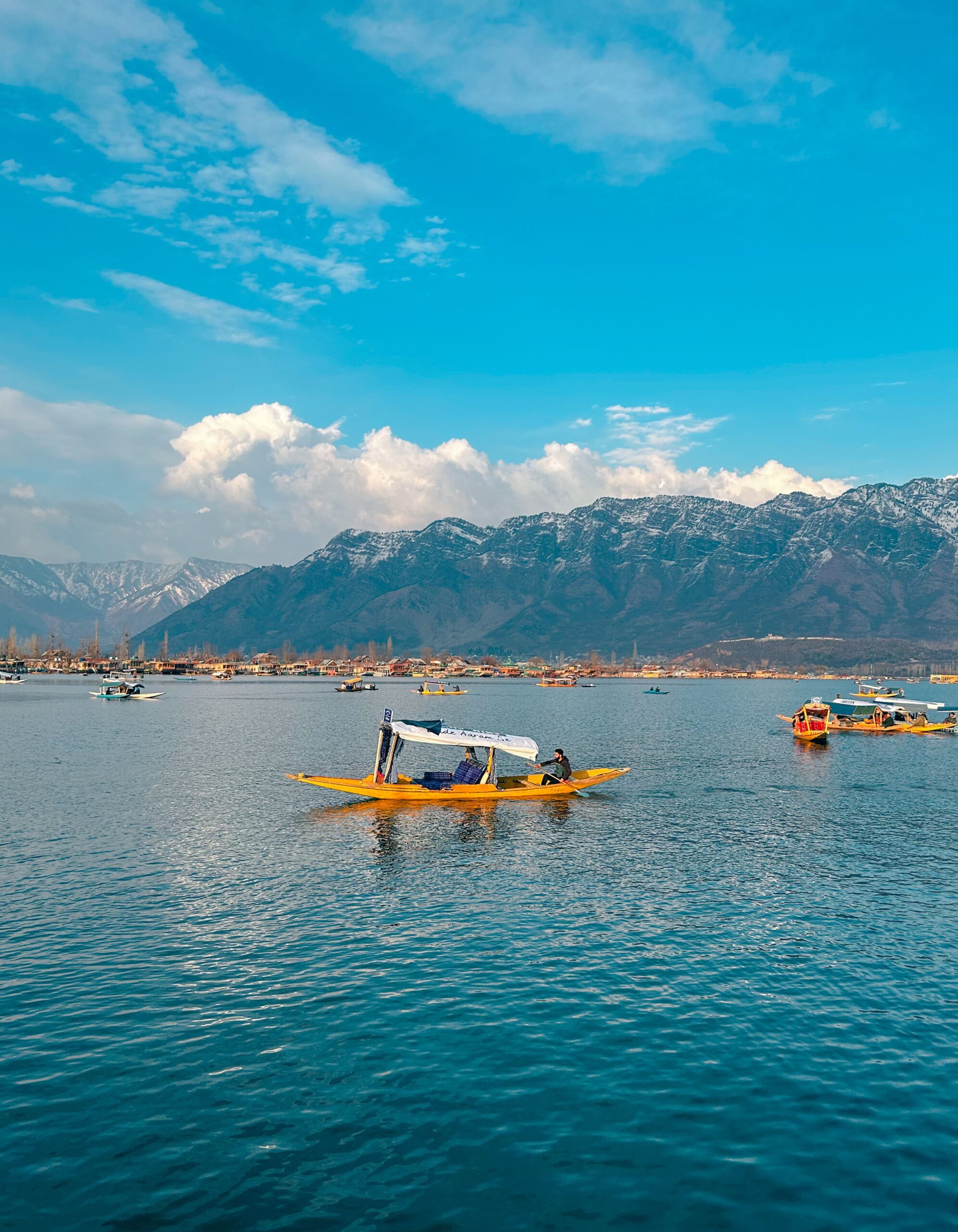 Beautiful Shikara boats on Dal Lake with a backdrop of the majestic Himalayas in Srinagar.