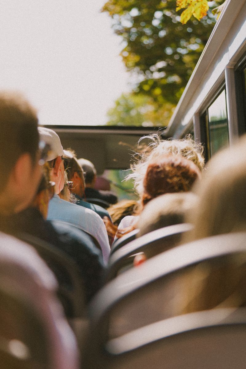 Group of people on an open-top tour bus enjoying a sunny day.