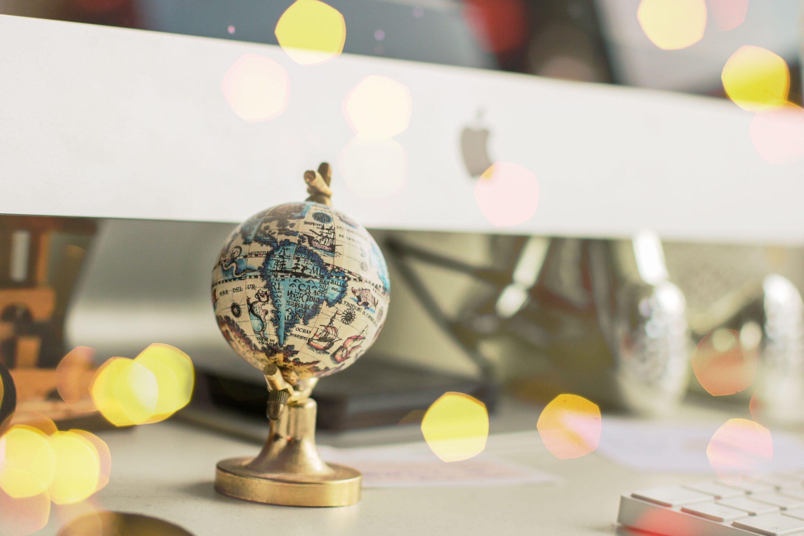 Close-up of a miniature globe on an office desk with a bokeh light effect, creating a dreamy atmosphere.